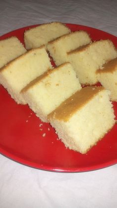 several pieces of cake on a red plate with white tablecloth and cloth behind it