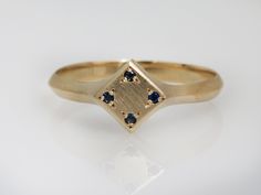 a yellow gold ring with blue sapphires on the sides and a diamond in the middle