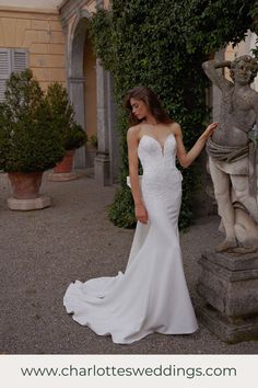 a woman in a wedding dress standing next to a statue