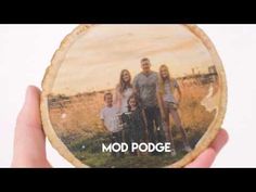 a hand holding up a wood slice with the words mod podge printed on it