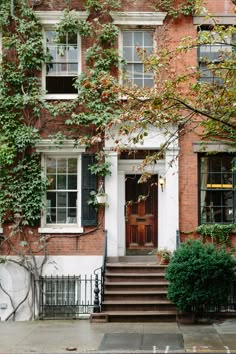 an old brick building with ivy growing on it's windows and steps leading up to the front door