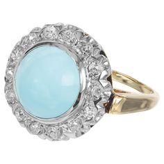 a ring with a blue stone surrounded by white and yellow gold accents on the sides