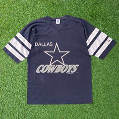 - 🏈 Vintage 1993 NFL Dallas Cowboys V Neck T-Shirt - 🎨 Navy blue tee in a large size - 🖼️ Features a prominent big graphic - ⭐ Authentic retro design from '93 - 🌟 Classic Cowboys team representation - 🏟️ Perfect for NFL enthusiasts - 🎉 Adds nostalgic sports vibe to your outfit - 💫 Comfortable and stylish wear - 🌈 Navy hue with bold graphic detail - 👕 Ideal for casual or game-day attire 📏Measurement:📏 Size on Tag: L Width (Pit to Pit): 21" Length (Neck to end of garment): 29" Sleeve Length (Neck to end of cuff): 18" 👕Condition: Good condition. Got yellow stain on sleeve. Please refer photos 🚚Shipping: Using Fedex Express shipping. 3-7 days delivery time 🚛Return: Please refer our policy E64-US4 Throwback Graphic Print Tops For Football Season, Retro Team Name T-shirt For Streetwear, College Throwback T-shirt With Team Logo, Retro Short Sleeve Tops With Team Logo, Vintage Graphic Print Football T-shirt, Vintage Graphic T-shirt For Football Season, Vintage Graphic Print T-shirt For Football Season, Vintage Crew Neck Top With Team Logo, Vintage Team Logo Tops For Streetwear