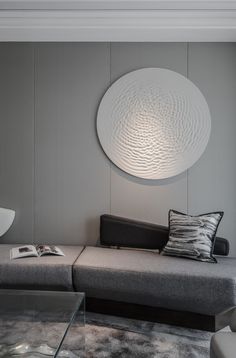 a living room with a couch, table and lamp on the wall in front of it