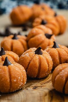 small pumpkin shaped pastries are on a wooden board with chocolate chips scattered around them