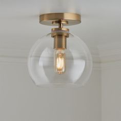 a light fixture with a clear glass globe on the bottom and an antique brass finish