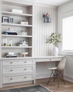 a white desk and chair in a small room with shelves on the wall behind it