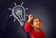 a young boy is smiling and holding his hand up to a light bulb drawn on a blackboard