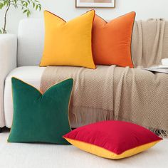 three pillows sitting on top of a white couch