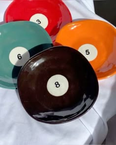 three different colored pool balls sitting on top of a white cloth covered table with numbers