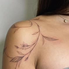 the back of a woman's shoulder with flowers and leaves tattoo on her left arm