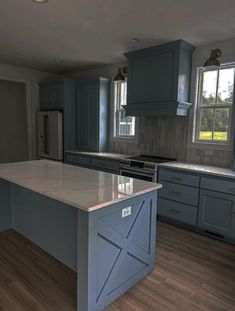 a large kitchen with blue cabinets and white counter tops, an island in the middle