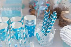 blue and white striped paper straws are sitting on a table next to cups, plates, and napkins