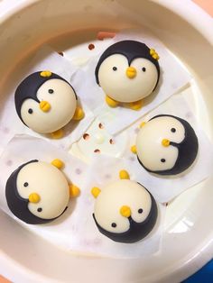 four little penguins are sitting in an ice cream dish with yellow and black frosting