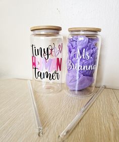 two glass jars with writing on them are sitting on a table next to a pair of scissors