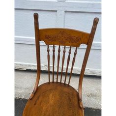 an old wooden chair sitting in front of a garage door, with the seat up