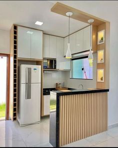 a kitchen with white cabinets and an island in front of the refrigerator freezer that is built into the wall