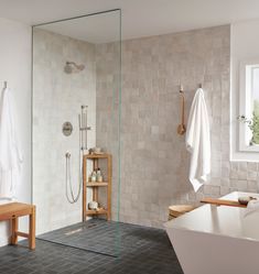 a bathroom with a walk in shower next to a white bath tub and wooden stools