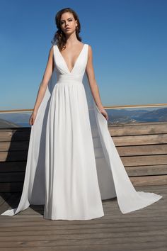 a woman standing on top of a wooden deck wearing a white dress