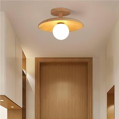 an empty hallway with wooden cabinets and white walls, along with a round light fixture on the ceiling