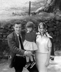 an old black and white photo of three people standing in front of a stone wall