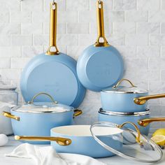 blue pots and pans with gold handles on a white countertop next to lemons