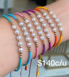 four bracelets with pearls and gold beads on the wrist, all in different colors