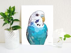 a blue and white bird sitting on top of a table next to a potted plant