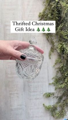 a person is holding a glass jar with christmas decorations on it and the words thrifted christmas gift idea