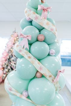 a christmas tree made out of balloons in a room with pink and blue decorations on it