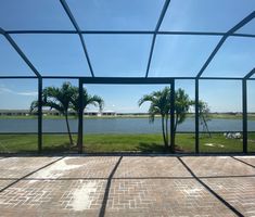 an empty patio with palm trees and water in the background