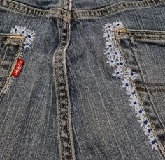 the back pocket of a pair of jeans with embroidered flowers on them and a red tag