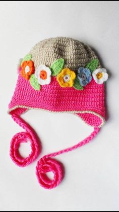 a crocheted hat with flowers on the brim is laying on a white surface