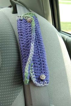 a purple crocheted scarf hanging from the back of a car seat in front of a window