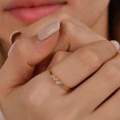 a close up of a person wearing a gold ring with three diamonds on the band