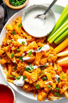 a white plate topped with cauliflower, carrots and celery sticks