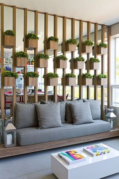 a living room filled with lots of furniture and plants on the wall above it's windows