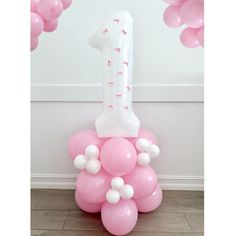 pink and white balloons are in the shape of a number one on top of a balloon column