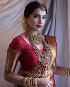 a woman in a red and gold sari with her hands on her hip, posing for the camera