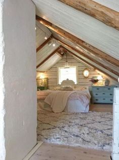 an attic bedroom with white walls and wood flooring on the ceiling is decorated in rustic style