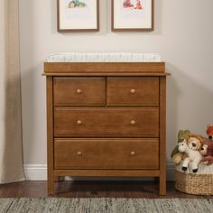 a baby crib with two stuffed animals in it and framed pictures on the wall