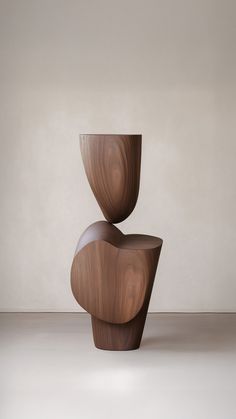 two wooden vases sitting on top of each other in front of a white wall