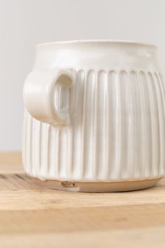 a white coffee cup sitting on top of a wooden table