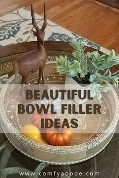 a bowl filled with fruit sitting on top of a glass table next to a deer figurine