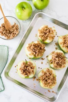 apples with crumbled toppings sitting on top of a baking sheet next to green apples