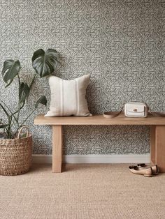 a wooden bench sitting next to a potted plant on top of a rug covered floor