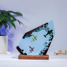 a glass sculpture on a wooden stand next to a potted plant and seashells