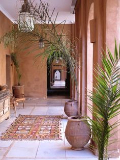 a hallway with potted plants and rugs on the floor