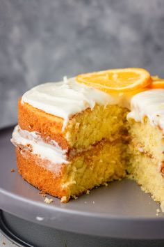 a cake with white frosting and an orange slice cut in half on a plate