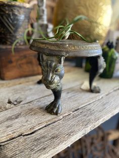 a cat figurine sitting on top of a wooden table next to a potted plant